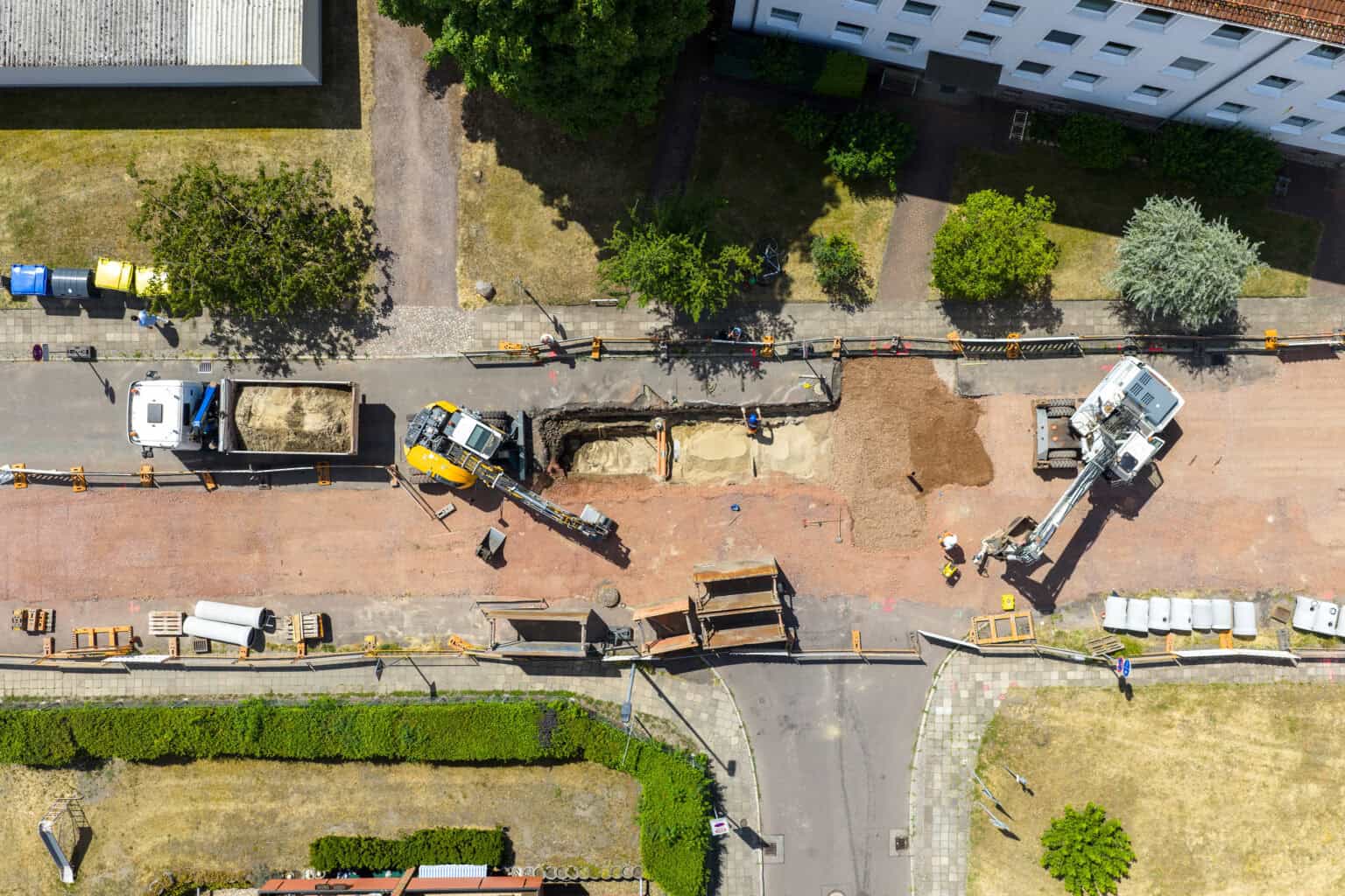 Luftaufnahme einer BGB-Baustelle: Leitungsgraben mit Bagger und Kran in einem Magdeburger Wohngebiet